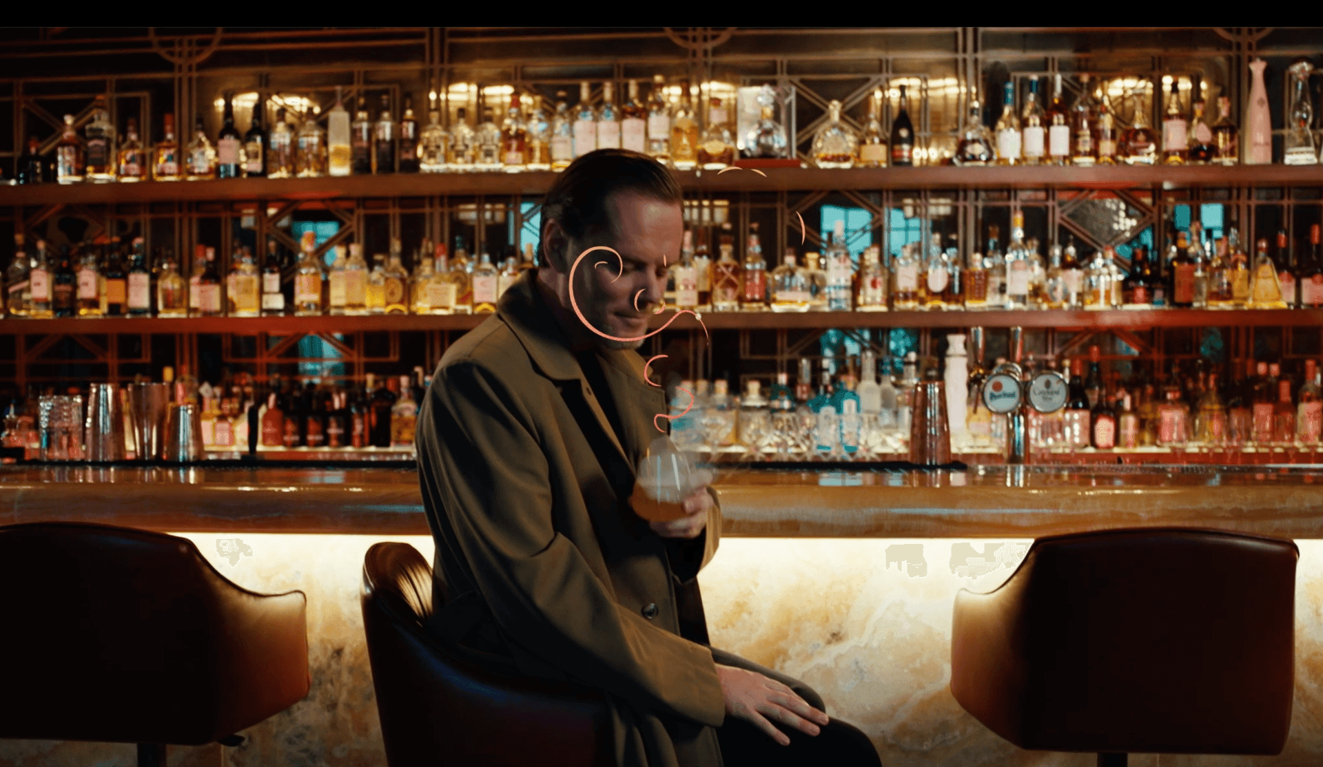 Person in a bar sipping a drink, surrounded by shelves of various liquor bottles in the background.
